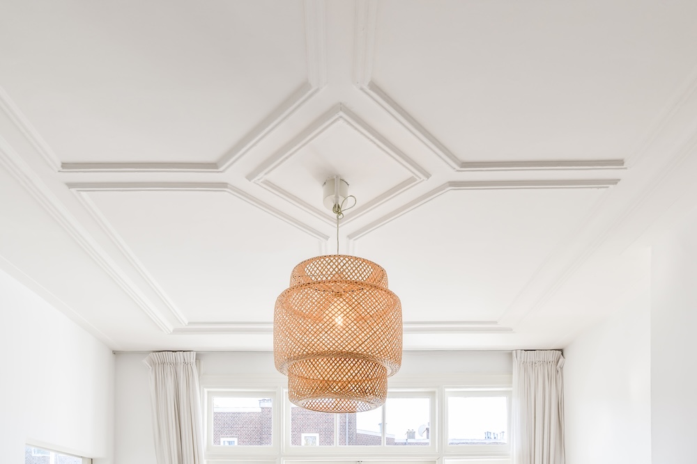 lampa z obudową koszykową na suficie z rozetą i sztukaterią rozeta na suficie i powieszona na środku lampa z kloszem koszykowym