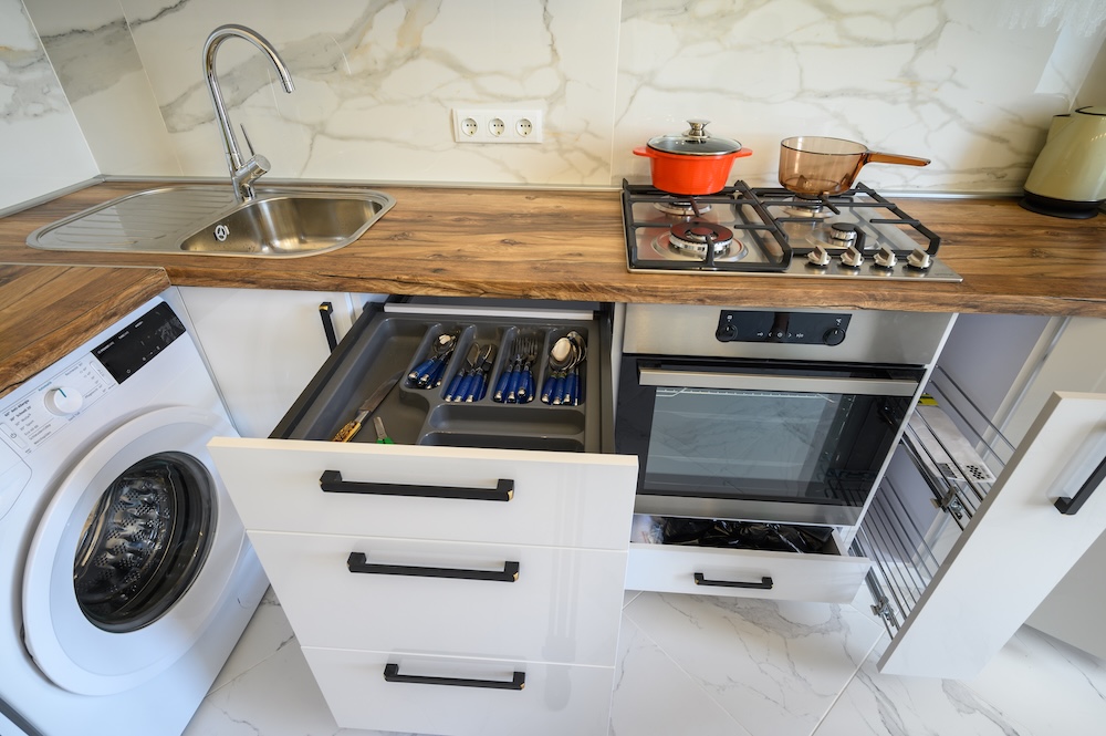mała kuchnia w bloku z pojemnymi szafkami i piekarnikiem  mała kuchnia w bloku ze sprzętami AGD i wysuwanymi szafkami