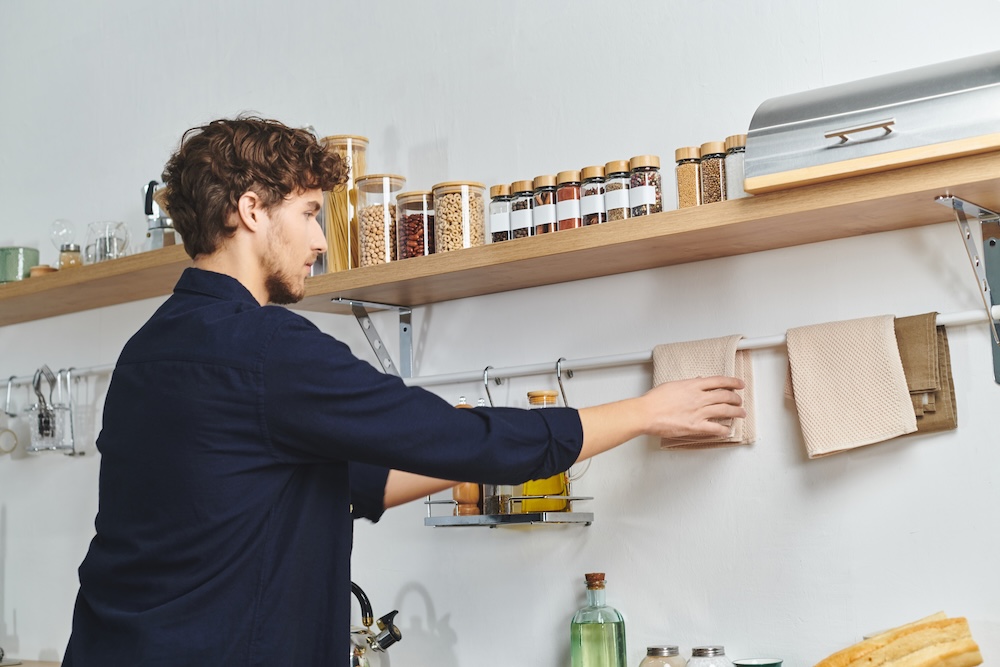 mała kuchnia w bloku - wykorzystanie ścian z półkami i drążkami do wieszania  mała kuchnia w bloku - półki ścienne na przyprawy i drążek na ściereczki