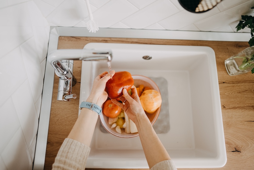 warzywa myte w zlewie w kuchni z kranem po lewej stronie  mycie warzyw w białym zlewie z boczną baterią