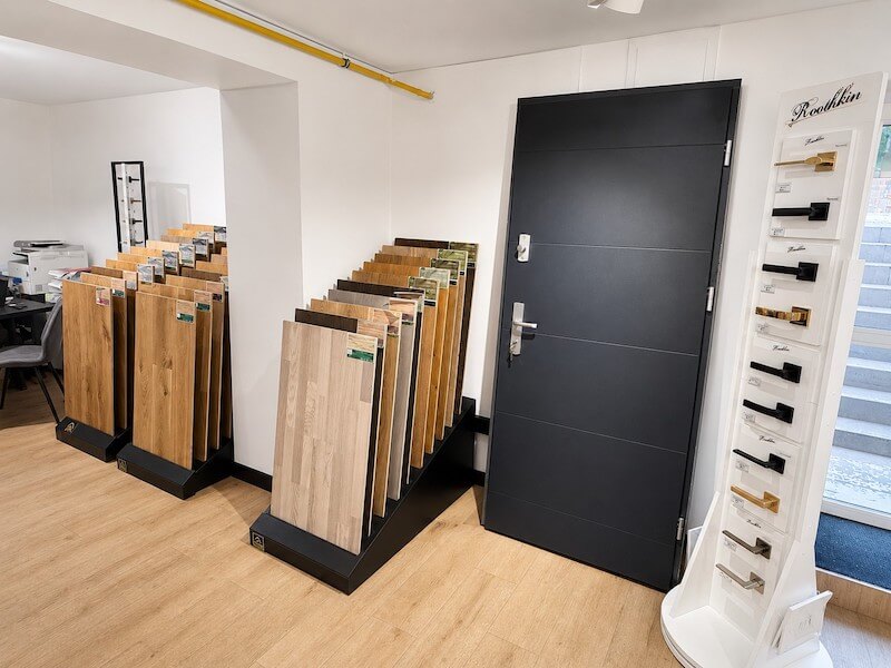 Ekspozycja drzwi i podłóg Ciemne drzwi, ekspozytor klamek i duże próbki podłóg w salonie Zip-Floors